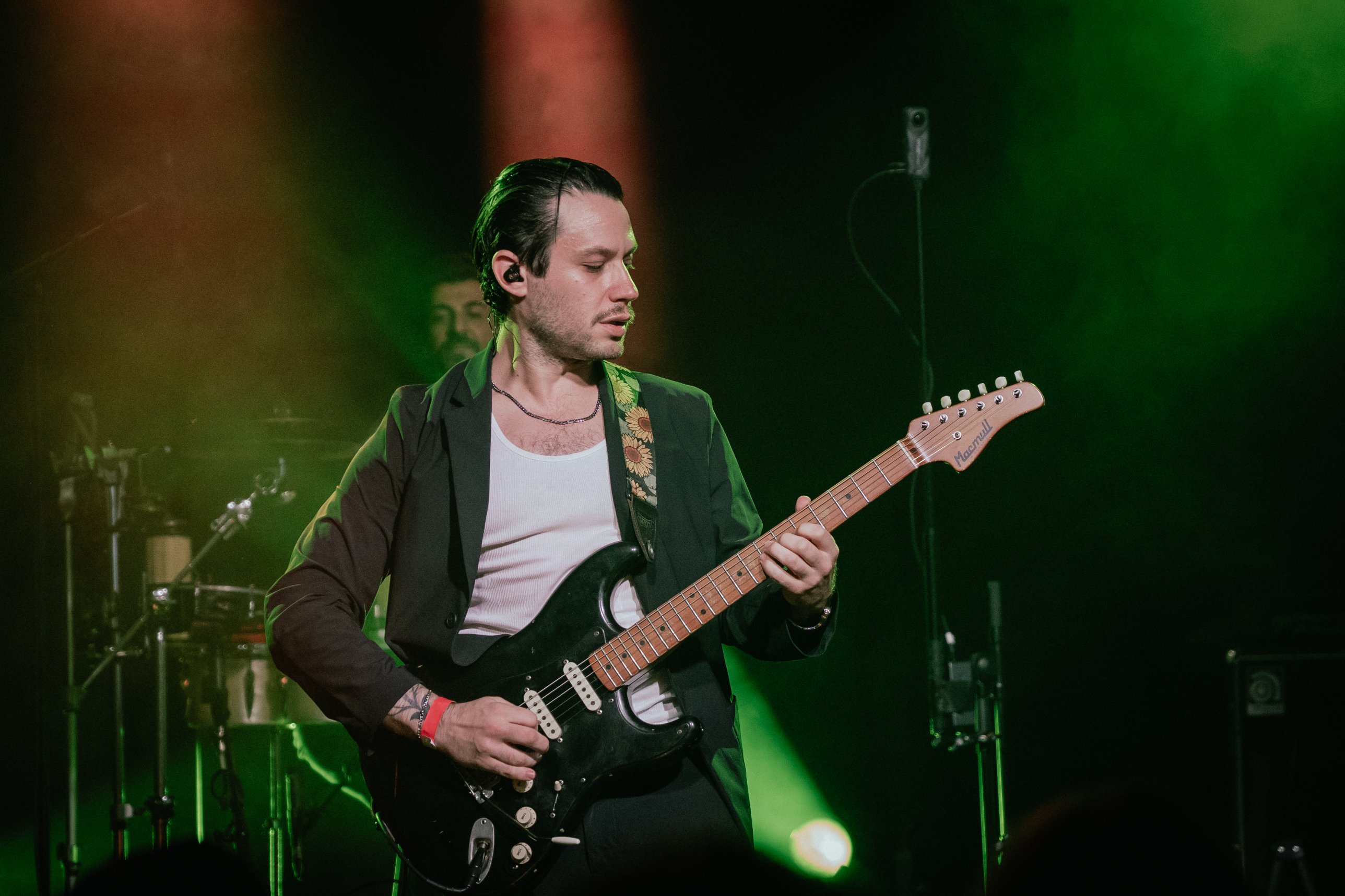 YUZ playing a black Stratocaster in green stage light